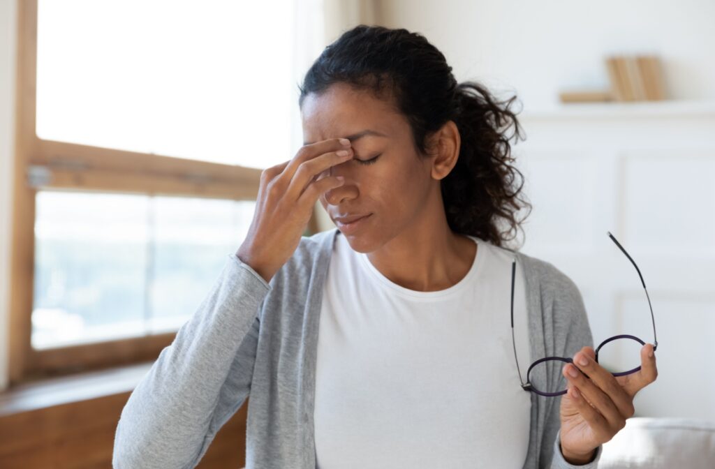 A young adult taking off their glasses and rubbing their sore eyes due to discomfort from a sinus infection.