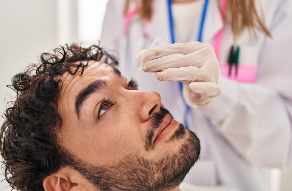 A person receives eye drops from a healthcare professional wearing gloves.