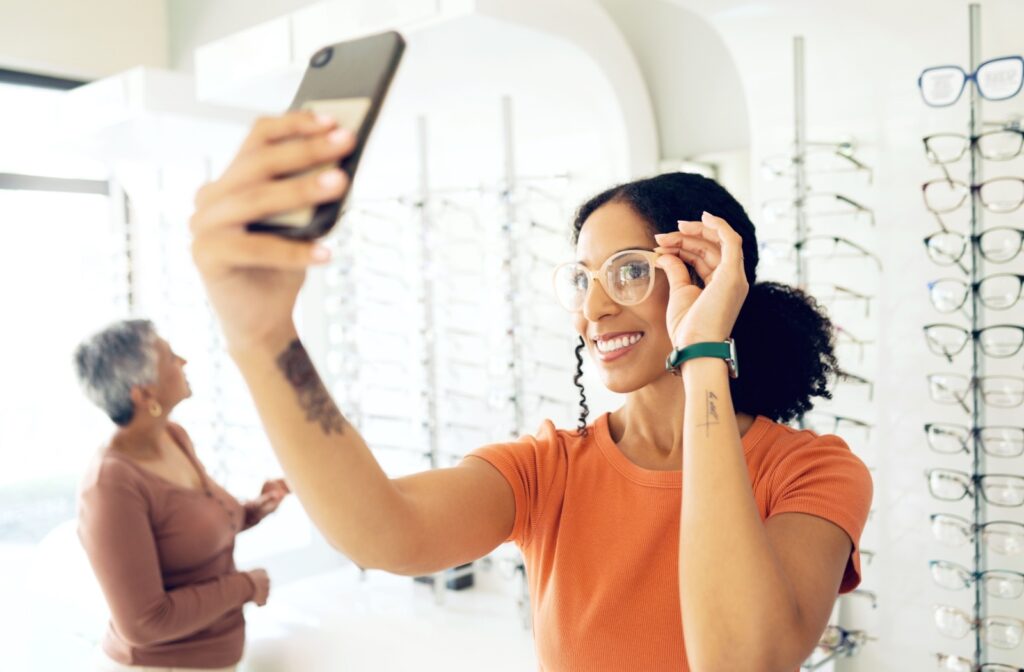 A young adult trying on new glasses frames at an optometry clinic.