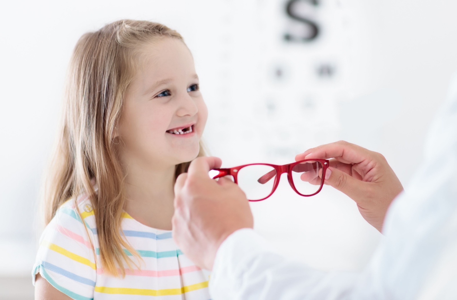 Young child sits in an optometrist getting fitting for anew pair of myopia glasses