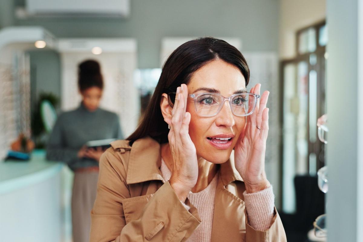 a person trying on a pair of clear frames at the optometrist